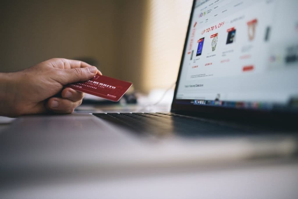 Description: Black and Gray Laptop Computer With Turned-on Screen Beside Person Holding Red Smart Card in Selective-focus Photography